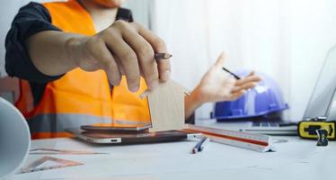 Dos colegas discutiendo el trabajo de datos y una tableta, un portátil con un proyecto arquitectónico en el sitio de construcción en un escritorio en la oficina foto