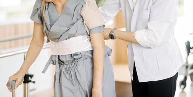 Physiotherapist helping senior woman with walker at remedial gymnastics photo