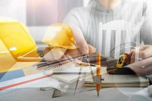 Two colleagues discussing data working and tablet, laptop with on on architectural project at construction site at desk in office photo