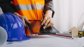 business hand working and laptop with on on architectural project at construction site at office desk in office photo