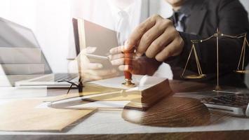 Justice and law concept.Male judge in a courtroom with the gavel, working with, computer and docking keyboard, eyeglasses, on table in morning light photo