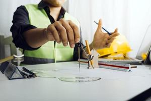 Dos colegas discutiendo el trabajo de datos y una tableta, un portátil con un proyecto arquitectónico en el sitio de construcción en un escritorio en la oficina foto