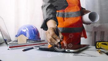 Two colleagues discussing data working and tablet, laptop with on on architectural project at construction site at desk in office photo