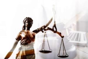 Justice and law concept.Male judge in a courtroom with the gavel, working with, computer and docking keyboard, eyeglasses, on table in morning light photo