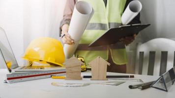 Two colleagues discussing data working and tablet, laptop with on on architectural project at construction site at desk in office photo