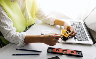 Two colleagues discussing data working and tablet, laptop with on on architectural project at construction site at desk in office photo