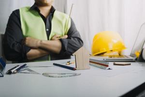 Two colleagues discussing data working and tablet, laptop with on on architectural project at construction site at desk in office photo