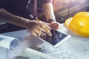 Two colleagues discussing data working and tablet, laptop with on on architectural project at construction site at desk in office photo