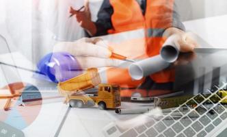 Two colleagues discussing data working and tablet, laptop with on on architectural project at construction site at desk in office photo