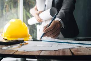 Two colleagues discussing data working and tablet, laptop with on on architectural project at construction site at desk in office photo