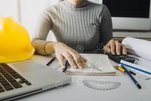 Two colleagues discussing data working and tablet, laptop with on on architectural project at construction site at desk in office photo