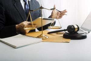 Justice and law concept.Male judge in a courtroom with the gavel, working with, computer and docking keyboard, eyeglasses, on table in morning light photo