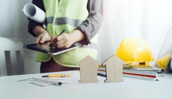 Two colleagues discussing data working and tablet, laptop with on on architectural project at construction site at desk in office photo