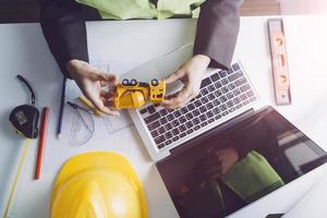 Two colleagues discussing data working and tablet, laptop with on on architectural project at construction site at desk in office photo