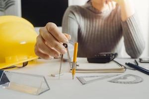 Two colleagues discussing data working and tablet, laptop with on on architectural project at construction site at desk in office photo