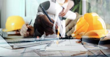 business hand working and laptop with on on architectural project at construction site at office desk in office photo