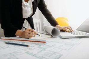 Two colleagues discussing data working and tablet, laptop with on on architectural project at construction site at desk in office photo