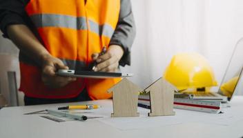 Two colleagues discussing data working and tablet, laptop with on on architectural project at construction site at desk in office photo
