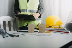 Two colleagues discussing data working and tablet, laptop with on on architectural project at construction site at desk in office photo