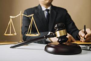 Justice and law concept.Male judge in a courtroom with the gavel, working with, computer and docking keyboard, eyeglasses, on table in morning light photo