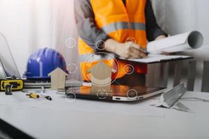 Two colleagues discussing data working and tablet, laptop with on on architectural project at construction site at desk in office photo