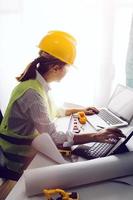 Two colleagues discussing data working and tablet, laptop with on on architectural project at construction site at desk in office photo