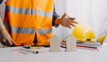 Two colleagues discussing data working and tablet, laptop with on on architectural project at construction site at desk in office photo