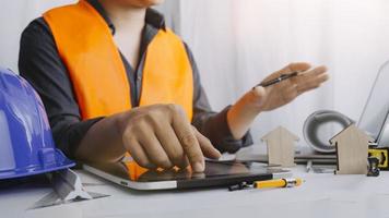 Two colleagues discussing data working and tablet, laptop with on on architectural project at construction site at desk in office photo