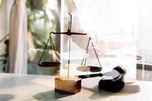 Justice and law concept.Male judge in a courtroom with the gavel, working with, computer and docking keyboard, eyeglasses, on table in morning light photo