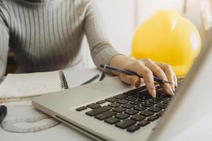 business hand working and laptop with on on architectural project at construction site at office desk in office photo