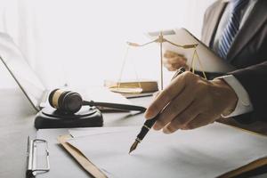 Justice and law concept.Male judge in a courtroom with the gavel, working with, computer and docking keyboard, eyeglasses, on table in morning light photo