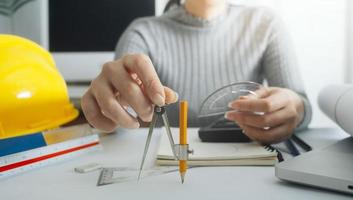 Dos colegas discutiendo el trabajo de datos y una tableta, un portátil con un proyecto arquitectónico en el sitio de construcción en un escritorio en la oficina foto