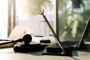 Justice and law concept.Male judge in a courtroom with the gavel, working with, computer and docking keyboard, eyeglasses, on table in morning light photo