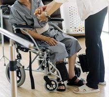 médico o enfermero cuidador con un anciano en silla de ruedas usando máscaras protectoras en casa o en un hogar de ancianos foto