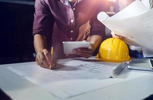 Two colleagues discussing data working and tablet, laptop with on on architectural project at construction site at desk in office photo
