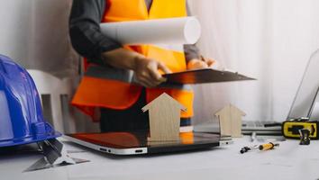 Two colleagues discussing data working and tablet, laptop with on on architectural project at construction site at desk in office photo