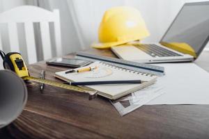 Two colleagues discussing data working and tablet, laptop with on on architectural project at construction site at desk in office photo