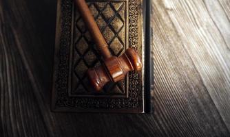 Justice and law concept.Male judge in a courtroom with the gavel, working with, computer and docking keyboard, eyeglasses, on table in morning light photo