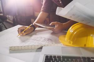 Two colleagues discussing data working and tablet, laptop with on on architectural project at construction site at desk in office photo