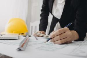 Two colleagues discussing data working and tablet, laptop with on on architectural project at construction site at desk in office photo