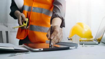 Two colleagues discussing data working and tablet, laptop with on on architectural project at construction site at desk in office photo