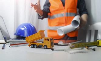 Two colleagues discussing data working and tablet, laptop with on on architectural project at construction site at desk in office photo