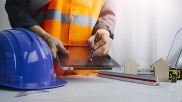 Two colleagues discussing data working and tablet, laptop with on on architectural project at construction site at desk in office photo