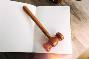 Justice and law concept.Male judge in a courtroom with the gavel, working with, computer and docking keyboard, eyeglasses, on table in morning light photo