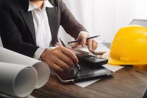 Two colleagues discussing data working and tablet, laptop with on on architectural project at construction site at desk in office photo