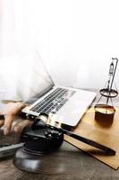 Justice and law concept.Male judge in a courtroom with the gavel, working with, computer and docking keyboard, eyeglasses, on table in morning light photo