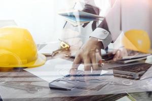 Two colleagues discussing data working and tablet, laptop with on on architectural project at construction site at desk in office photo