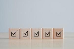 Checklist Survey and assessment. Quality Control. Goals achievement and business success. Check mark icon on wooden blocks. photo
