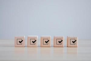 Checklist, Task list, Survey and assessment. Quality Control. Goals achievement and business success. Check mark icon on wooden blocks. photo