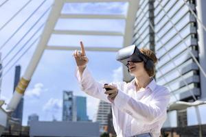 Young caucasian woman wearing VR goggles to play virtual reality simulator game surrounded by modern urban downtown city building photo